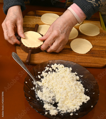 Obraz na płótnie Woman skillfully fills dough circles with cheese in a warm kitchen w salonie