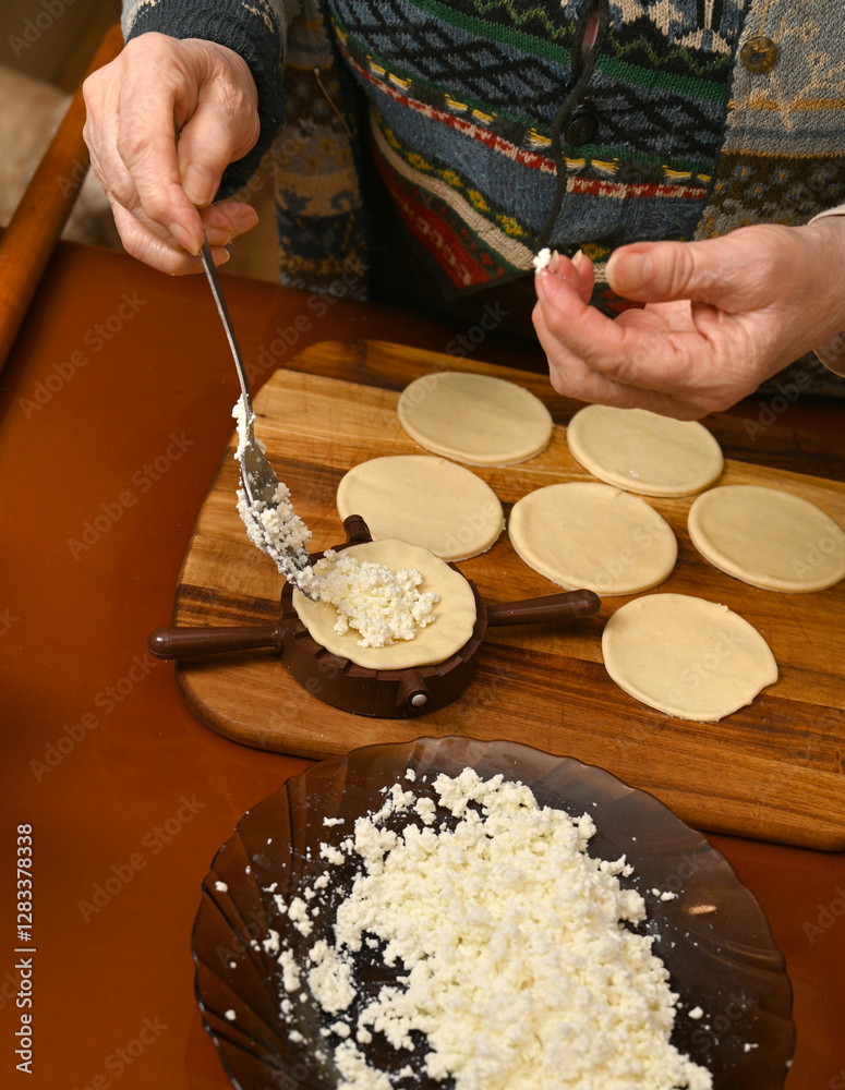 Woman skillfully fills dough circles with cheese in a warm kitchen.