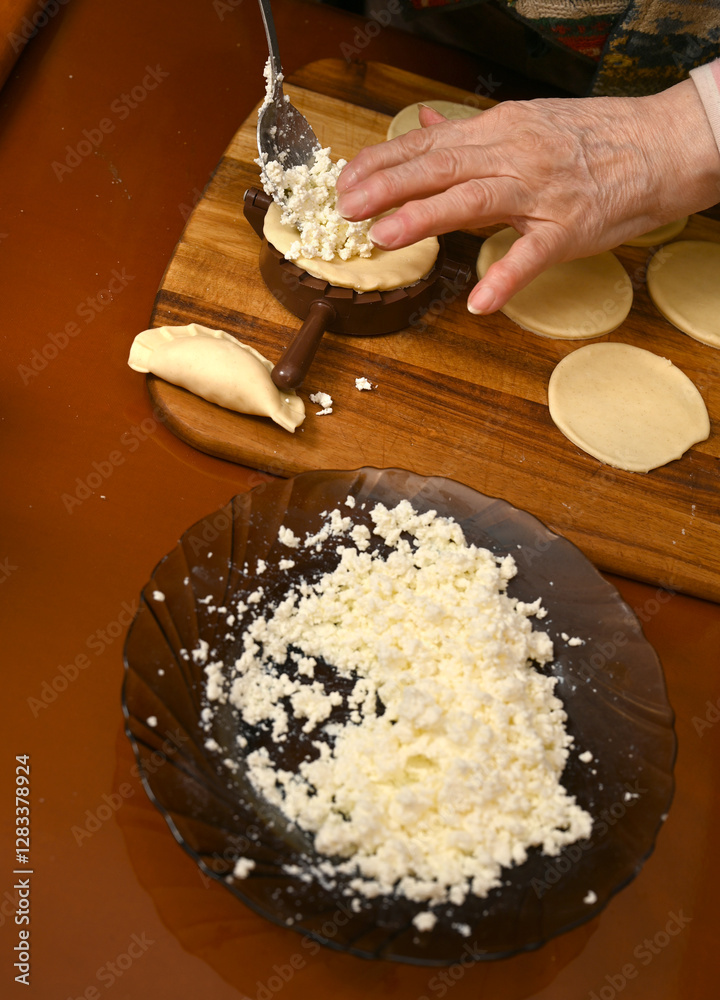 Woman skillfully fills dough circles with cheese in a warm kitchen.