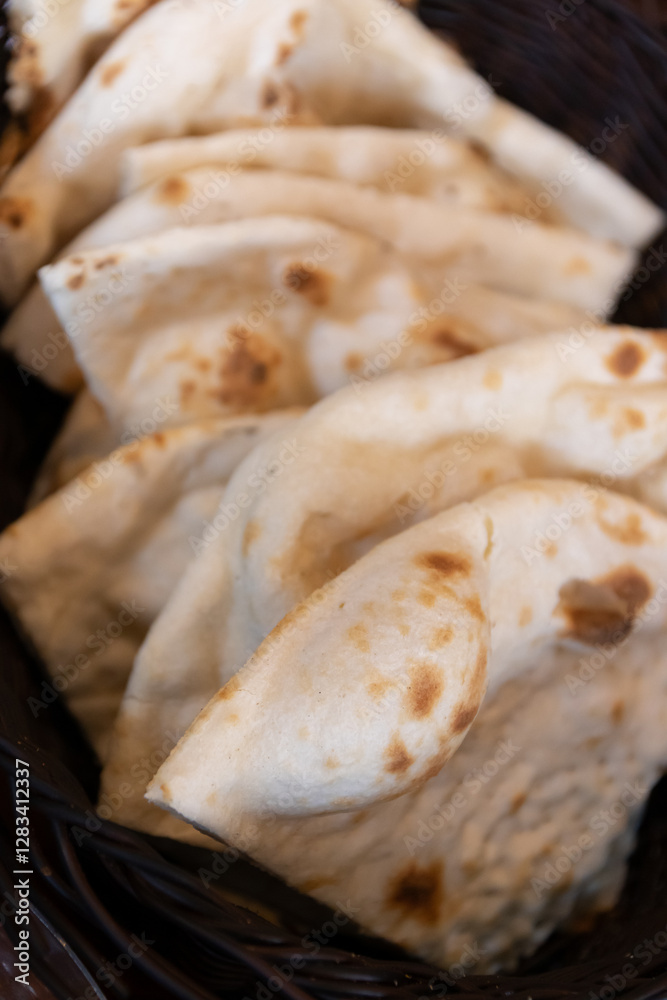 Freshly baked naan bread in a woven basket. Freshly baked naan bread in a woven basket.