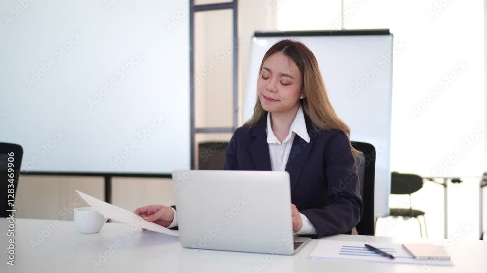 Young Asian businesswoman in a formal suit having a video conference on a laptop in a modern office Young Asian businesswoman in a formal suit having a video conference on a laptop in a modern office