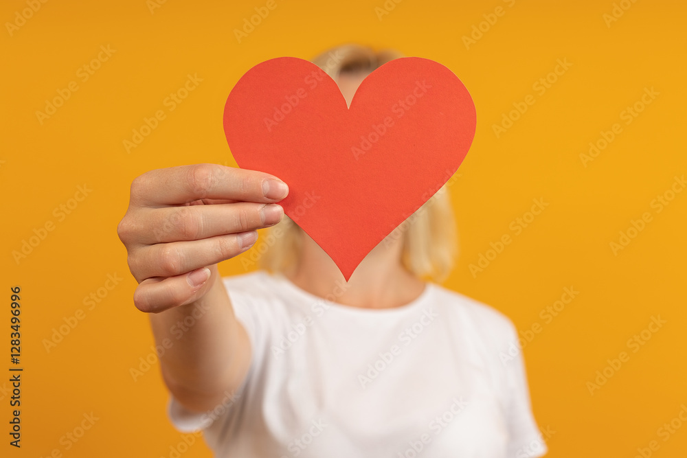 a man with white hair and a white t-shirt holds a paper heart in front of his face on valentine's day a man with white hair and a white t-shirt holds a paper heart in front of his face on valentine's day