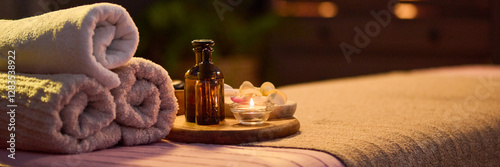 Website banner of three towel rolls, oval tray with jar filled with essential oil and lit tea candle