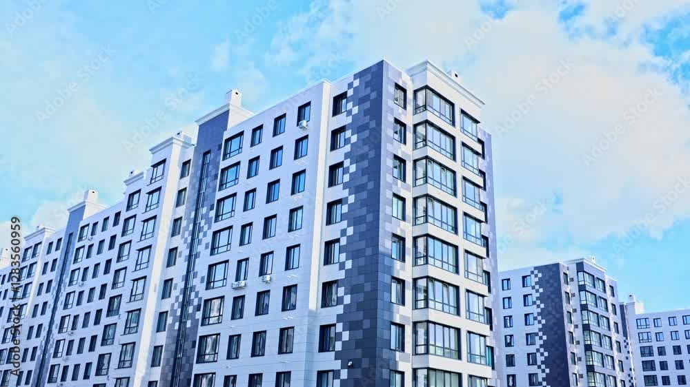 Multi-storey apartment buildings of the modern architectural style of the residential complex in gray and white colors stand parallel to each other, the camera smoothly moves to the side against the Multi-storey apartment buildings of the modern architectural style of the residential complex in gray and white colors stand parallel to each other, the camera smoothly moves to the side against the