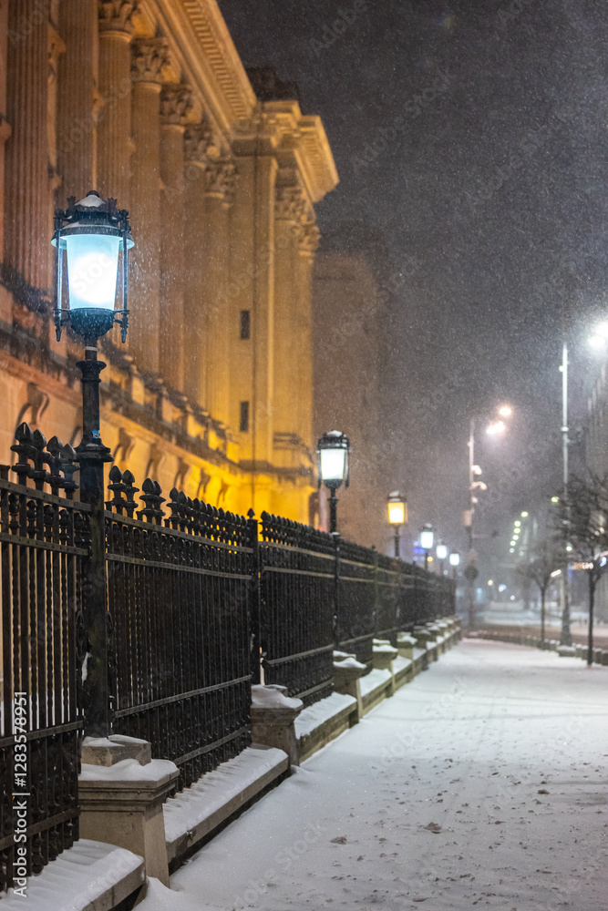 Winter in Bucharest. A snow-covered street in Bucharest illuminated by vintage street lamps, casting warm light on the cold winter night.