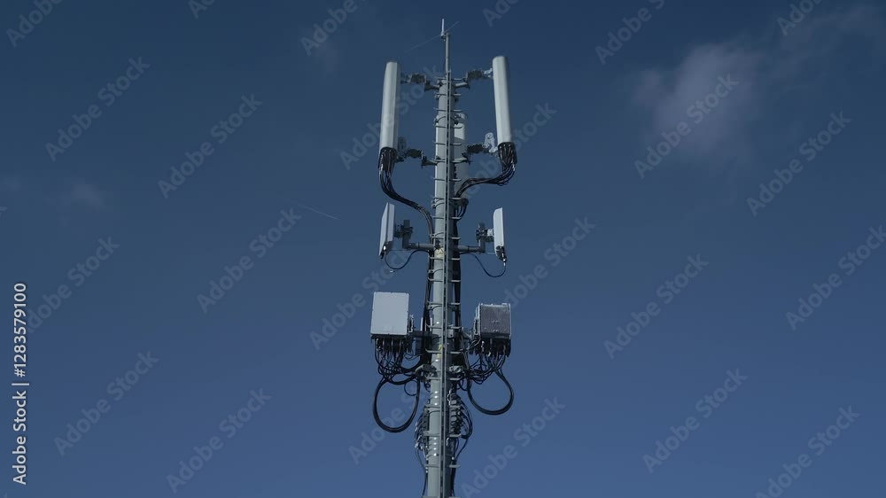 A modern cell tower stands tall against a clear blue sky, showcasing technological progress A modern cell tower stands tall against a clear blue sky, showcasing technological progress