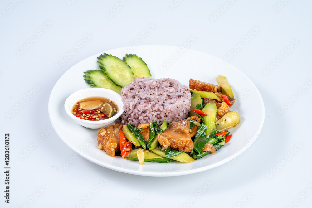 Delicious plate of purple rice with stir fried vegetables, crispy pork, and cucumber slices, served with side of dipping sauce for flavorful meal Delicious plate of purple rice with stir fried vegetables, crispy pork, and cucumber slices, served with side of dipping sauce for flavorful meal