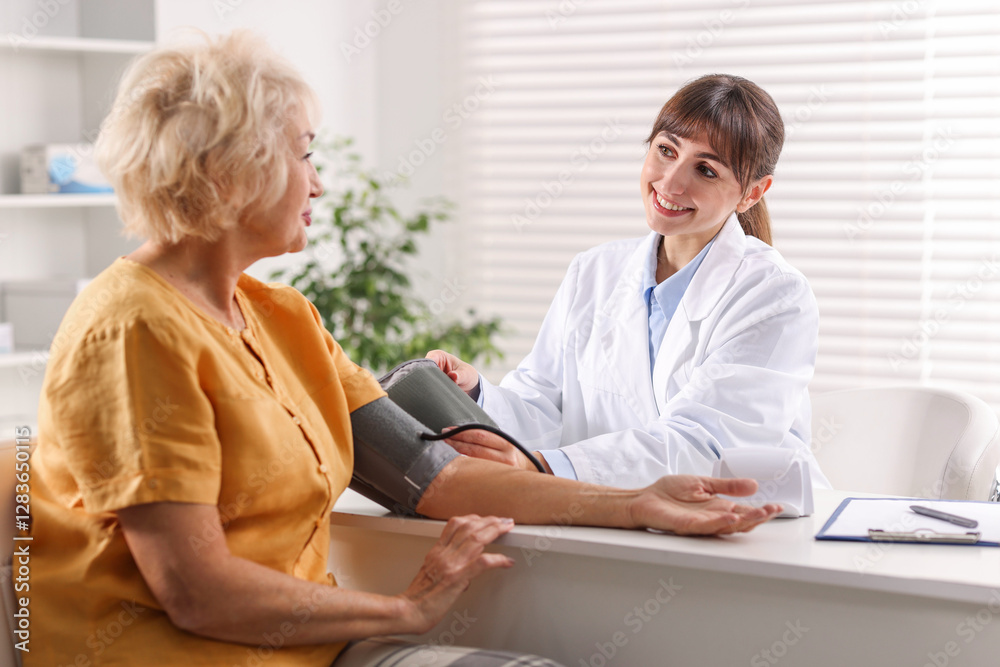 Doctor measuring senior woman's blood pressure during appointment in hospital Doctor measuring senior woman's blood pressure during appointment in hospital