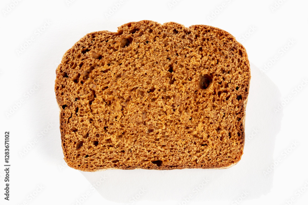 Slice of fresh dark bread on white background in sunlight close up Slice of fresh dark bread on white background in sunlight close up