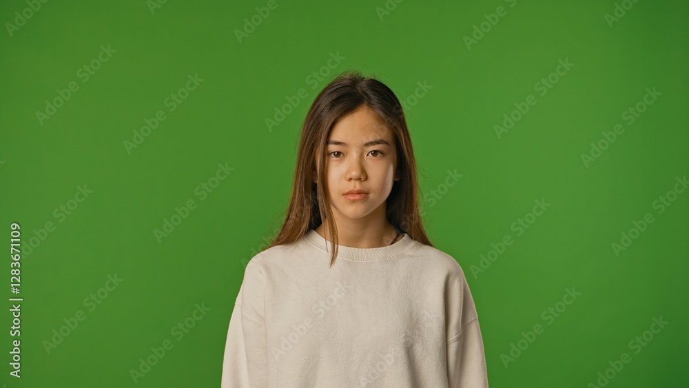 Asian girl child in shirt standing looking at camera, neutral expression, isolated on chroma key green screen studio background mockup. Asian girl child in shirt standing looking at camera, neutral expression, isolated on chroma key green screen studio background mockup.