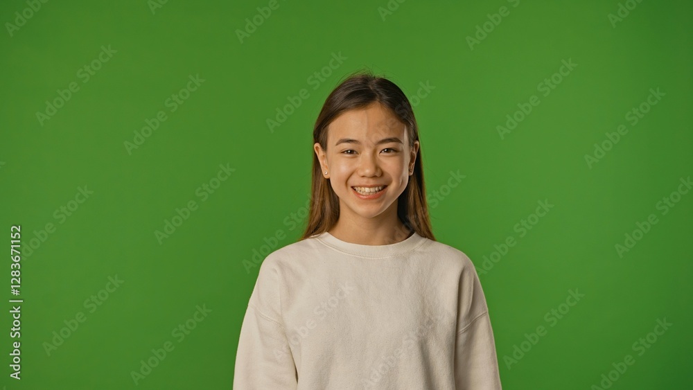 Asian girl child in shirt standing looking at camera and smiling, positive expression, isolated on chroma key green screen studio background mockup. Asian girl child in shirt standing looking at camera and smiling, positive expression, isolated on chroma key green screen studio background mockup.