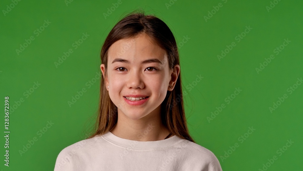 Asian girl child in shirt standing looking at camera and smiling, positive expression, isolated on chroma key green screen studio background mockup. Asian girl child in shirt standing looking at camera and smiling, positive expression, isolated on chroma key green screen studio background mockup.
