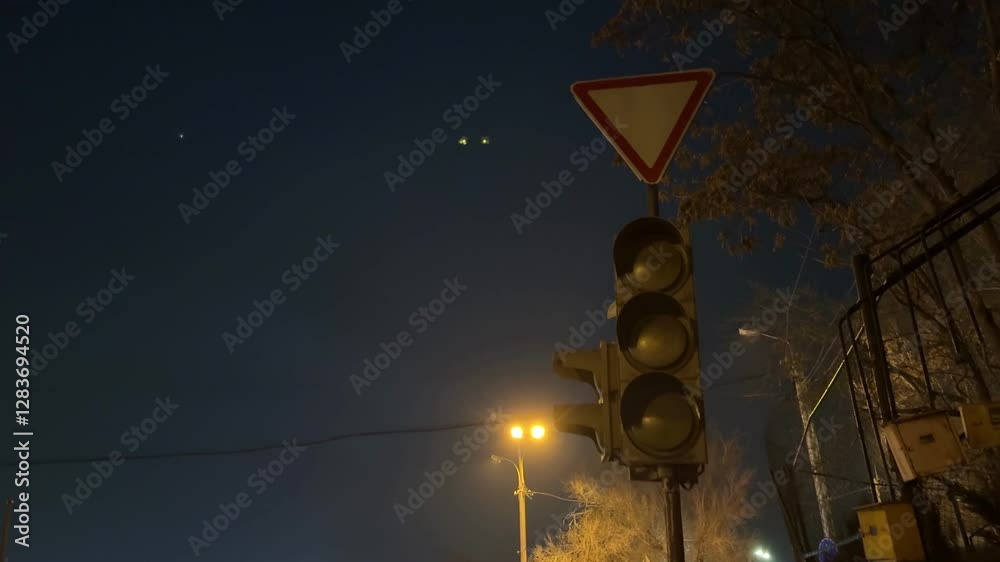 A non-working traffic light flashes yellow warning to stop and let traffic pass and a sign yield to give way to vehicles