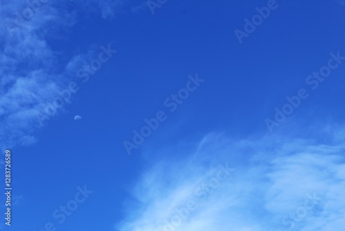 Fototapeta Naklejka Na Ścianę i Meble -  The morning blue sky is decorated with white clouds and the moon is still visible.