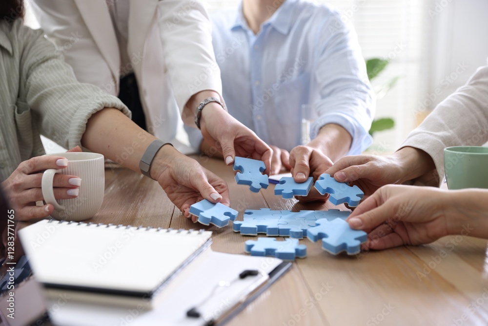 Unity concept. People putting puzzle pieces together at wooden table indoors, closeup Unity concept. People putting puzzle pieces together at wooden table indoors, closeup