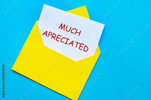 Yellow envelope on a blue cover with a white card partially pulled out with Much Appreciated text