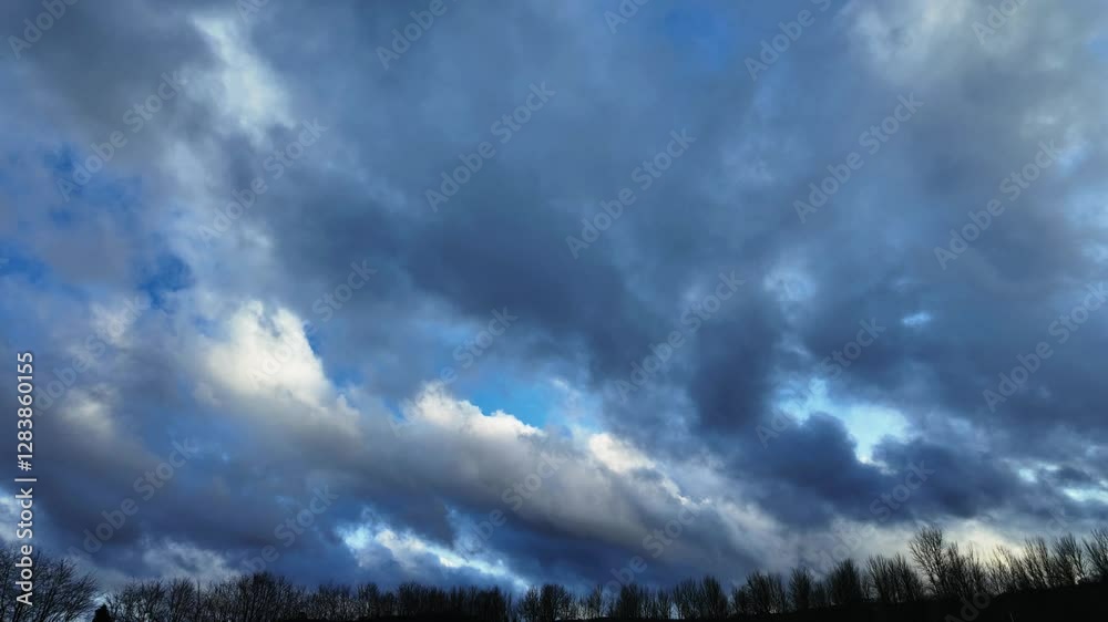 Cloud timelapse in clear blue sky over silhouetted forest in the countryside of Derbyshire