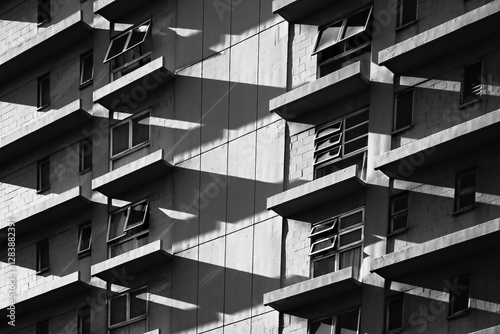  High contrast architectural fine art abstraction. A black-and-white photograph of a building facade, emphasizing geometric patterns and shadows. 