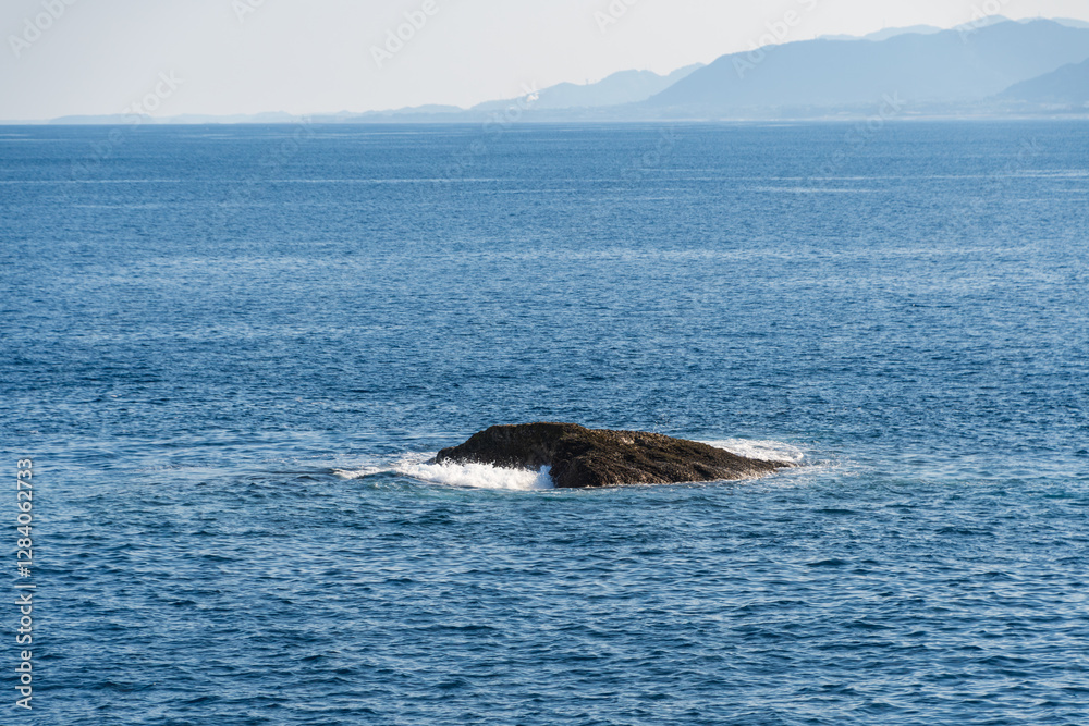 Fototapeta premium 海に浮かぶ孤岩と波の風景