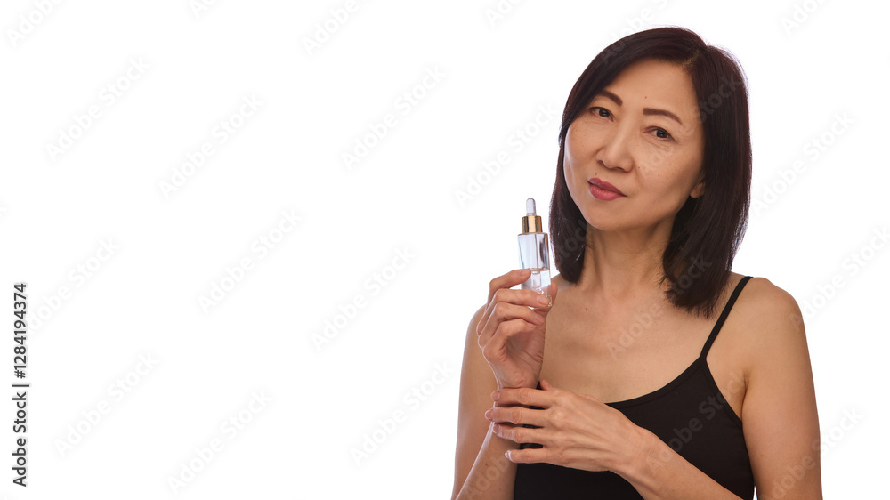 Portrait of beautiful mature Korean woman in her 60s with healthy skin, holding serum bottle isolated on white background. Rejuvenation. Concept of skin care, anti-aging treatment, cosmetology Portrait of beautiful mature Korean woman in her 60s with healthy skin, holding serum bottle isolated on white background. Rejuvenation. Concept of skin care, anti-aging treatment, cosmetology