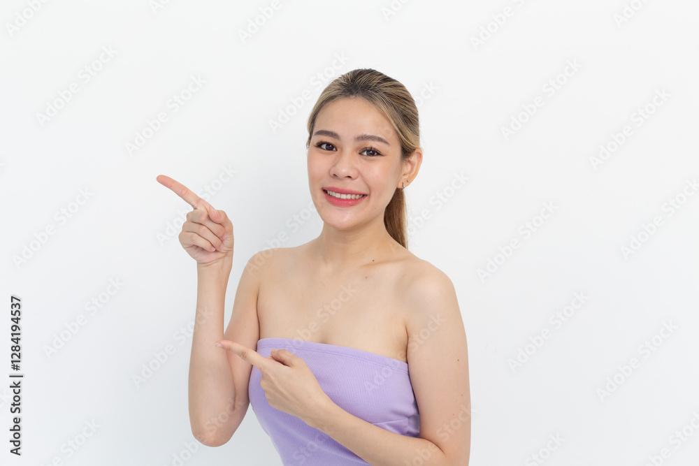 portrait of a Happy Asian woman smiling points her index finger at an empty space in the background and looks straight ahead on white background portrait of a Happy Asian woman smiling points her index finger at an empty space in the background and looks straight ahead on white background