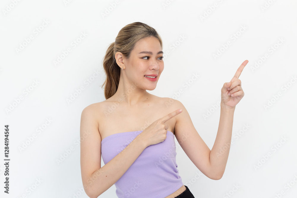 portrait of a Happy Asian woman smiling points her index finger at an empty space in the background and looks straight ahead on white background portrait of a Happy Asian woman smiling points her index finger at an empty space in the background and looks straight ahead on white background
