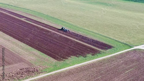 Bauer pflügt ein Feld, Vogelscharen begleiten den Traktor