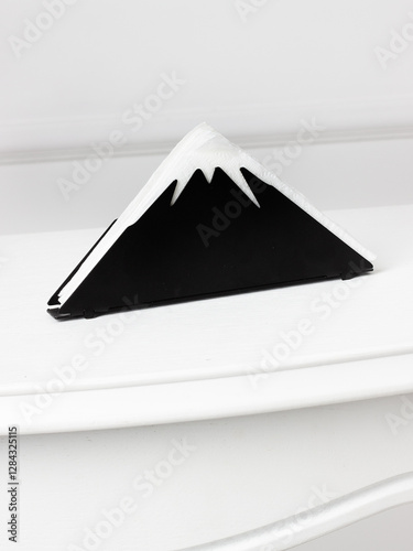 Stylish napkin holder designed in the shape of a mountain with a black base and white snow-capped peak.