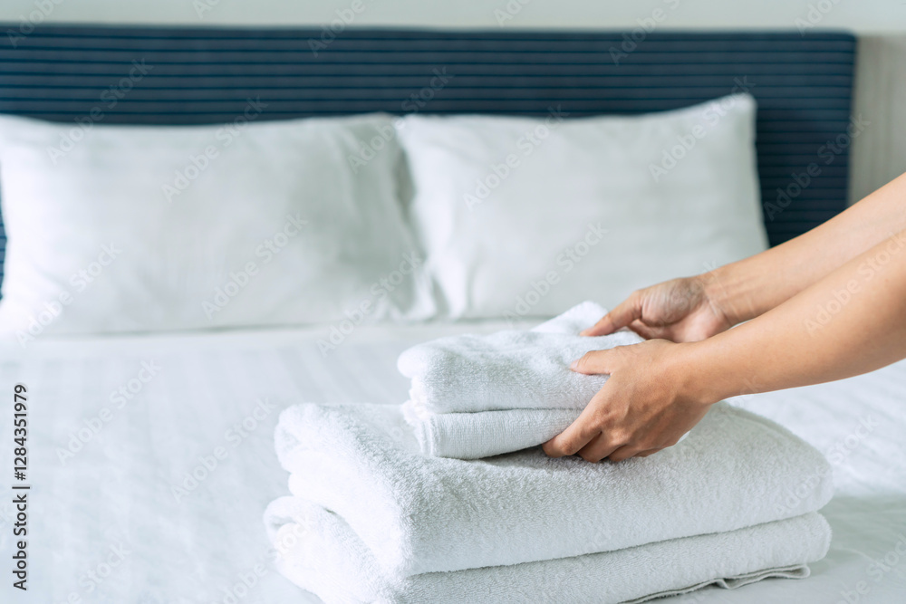 Close up of maid hands set up bed and towel in hotel room, copy space for text Close up of maid hands set up bed and towel in hotel room, copy space for text