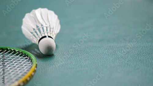 Badminton racket and white shuttlecock on green badminton court