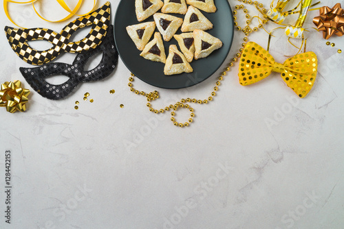 Purim holiday background with carnival mask, party decoration and hamantaschen cookies on plate. Top view, flat lay photo