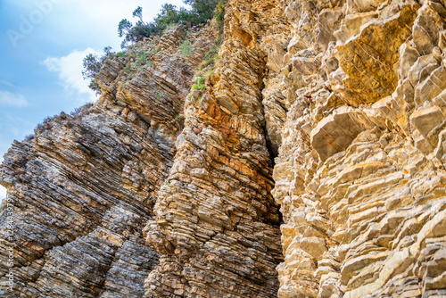 Layered rock texture in Budva, Montenegro. Sedimentary rocks with rugged surface of gray and brown. Natural formation of layers and cracks, geological structure. photo