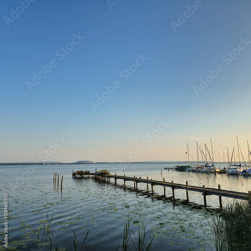 A Serene and Beautiful Waterfront View featuring a Pier, Sailboats gently floating at Sunset Steinhuder Meer
