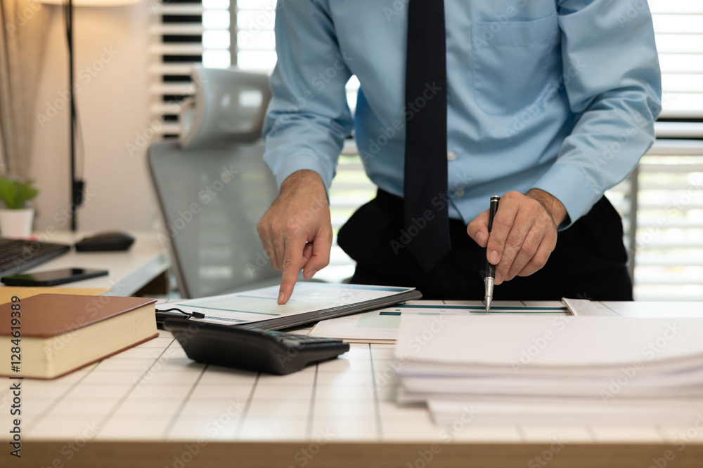 A man is pointing at a piece of paper on a desk. The paper has a business-related title and the man is looking at it intently
A man is pointing at a piece of paper on a desk. The paper has a business-related title and the man is looking at it intently