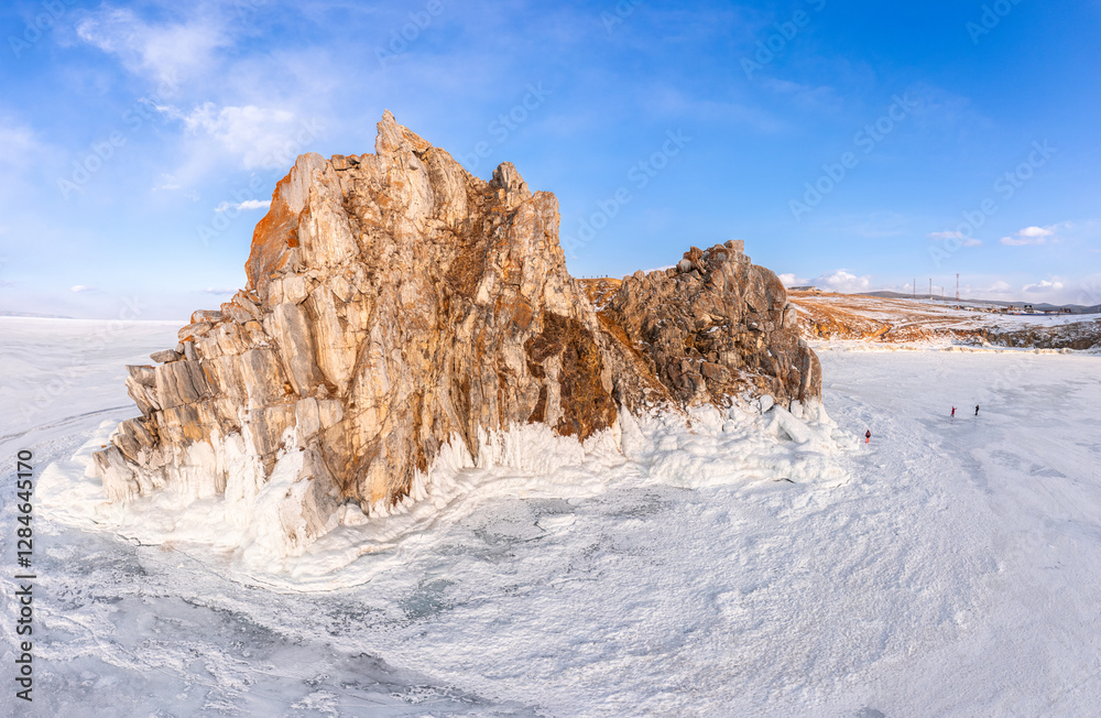 Aerial top view to famous Shamanka rock and small sea covered with snow. Winter landscape. Popular touristic destination, Clear ice. Cape Burkhan on Olkhon island, frozen Baikal lake, Siberia, Russia. Aerial top view to famous Shamanka rock and small sea covered with snow. Winter landscape. Popular touristic destination, Clear ice. Cape Burkhan on Olkhon island, frozen Baikal lake, Siberia, Russia.