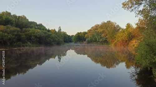Morning sunrise over the river. Fog over the river at dawn. Wonderful summer landscape. The river is covered with fog at dawn. Forest is reflected in the river in summer