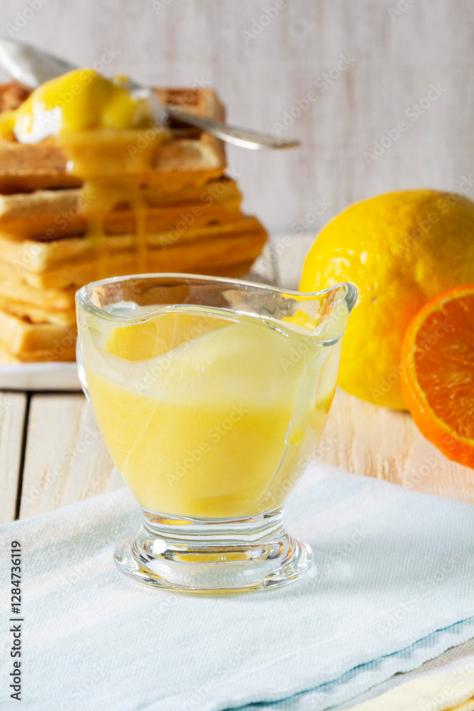 Lemon-tangerine curd in a glass gravy boat, tangerine and lemon and Belgian waffles.
