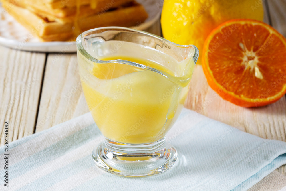 Lemon-tangerine curd in a glass gravy boat, tangerine and lemon and Belgian waffles.