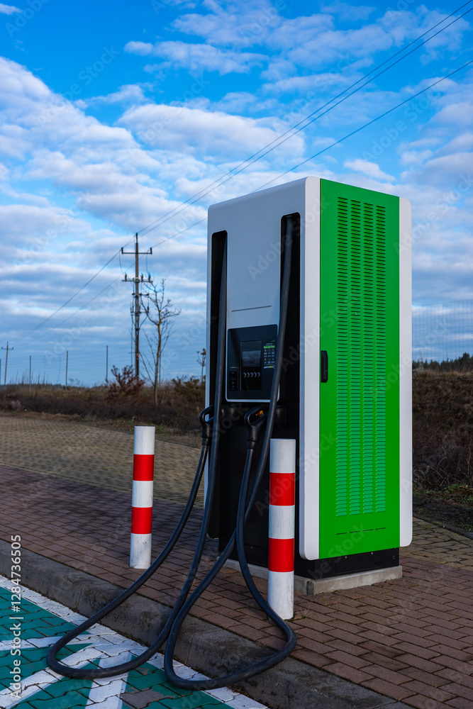 An electric car charger at a drivers' rest area on a motorway. The photo was taken on a sunny day.