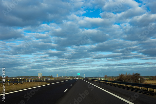 Obraz na płótnie Blue sky and delicate clouds over the highway. The photo was taken on a sunny day. w salonie