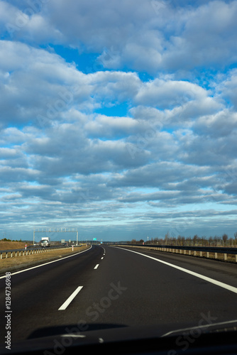 Obraz na płótnie Blue sky and delicate clouds over the highway. The photo was taken on a sunny day. w salonie