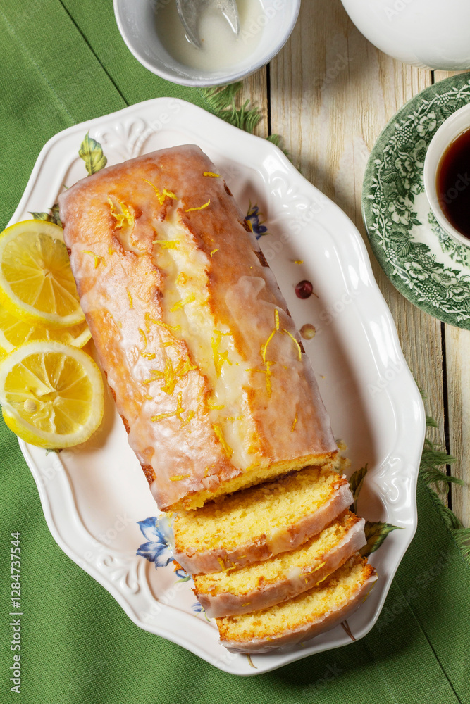 Aromatic lemon cake, covered with sugar icing and sprinkled with zest, served with tea.