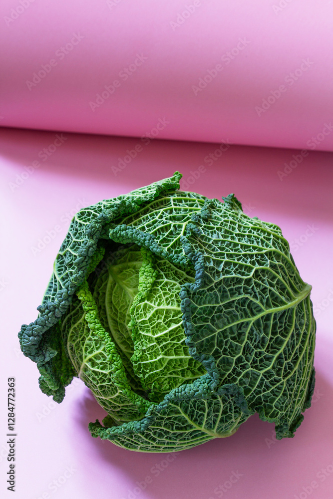 Textured Savoy cabbage on light pink cardboard.
