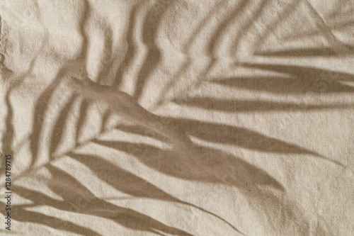 Fototapeta Naklejka Na Ścianę i Meble -  Tropical palm tree leaves shadow on sand color linen background. Minimal summer concept. An original backdrop image with a play of light and shadow. Creative copy space. Summer aesthetic. Flat lay.