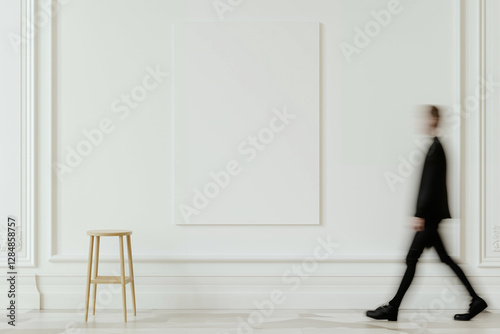 Person walking in modern interior with blank canvas. Man in black suit walking past white wall with empty frame and wooden stool. Blurred figure in contemporary art gallery