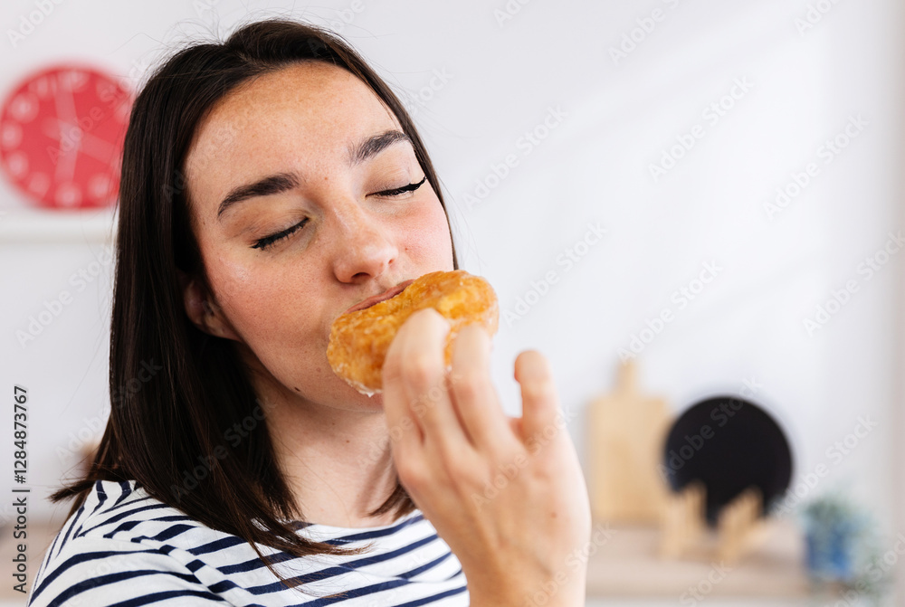 Woman enjoying sweet taste of donut with closed eyes, experiencing moment of bliss in her kitchen Woman enjoying sweet taste of donut with closed eyes, experiencing moment of bliss in her kitchen