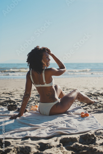 Athletic young woman in a bikini sunbathing and relaxing at the beach photo