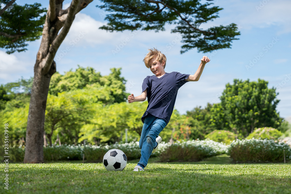 Little boy playing football in the garden with morning sunrise Little boy playing football in the garden with morning sunrise