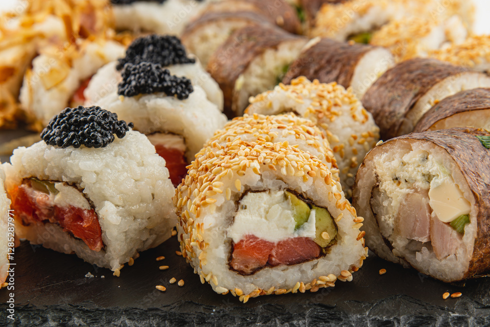 Delicious sushi rolls featuring various fillings served on a black stone plate Delicious sushi rolls featuring various fillings served on a black stone plate