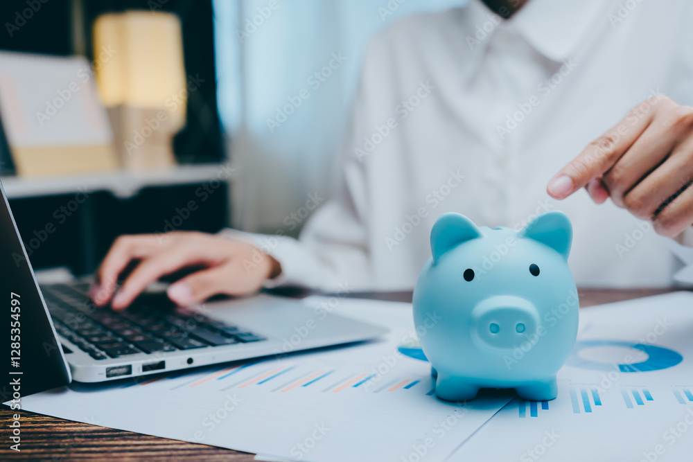 Young Professional Saving Money with Blue Piggy Bank and Laptop, business concept Young Professional Saving Money with Blue Piggy Bank and Laptop, business concept